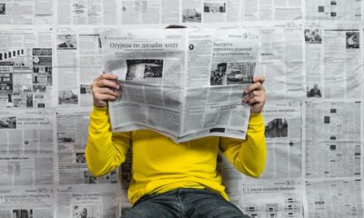 a person sitting on the floor reading a newspaper